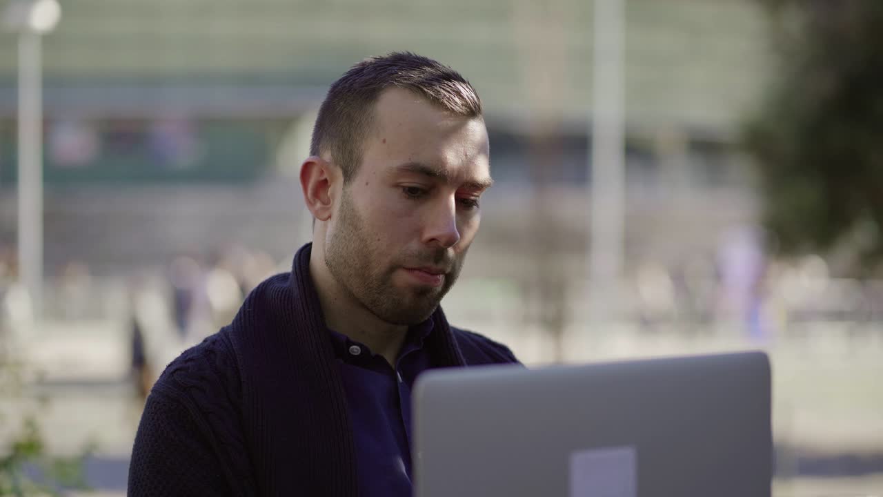 joven pensativo trabajando con una computadora portátil al aire libre