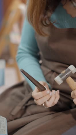close-up of hands crafting jewelry with hammer and punch