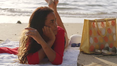 mujer latina morena en la playa tropical a orillas del mar tumbada en el frente relajándose bajo el sol, plano medio