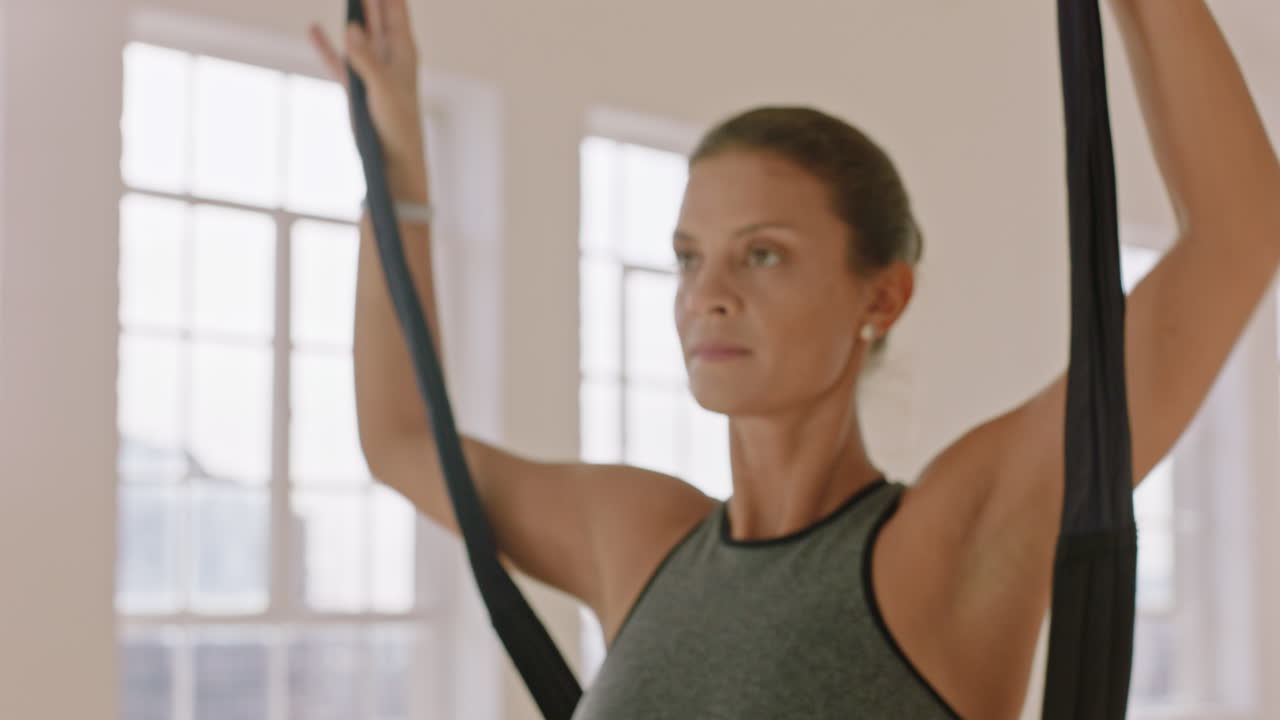 mujer de yoga aéreo practicando la postura de mariposa invertida colgando boca abajo usando una hamaca disfrutando de un estilo de vida de acondicionamiento físico saludable haciendo ejercicio en el estudio entrenando meditación al amanecer