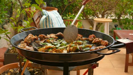 Pan-shot-during-Traditional-paella-preparation,-from-the-Valencian-region-with-chicken-and-vegetables