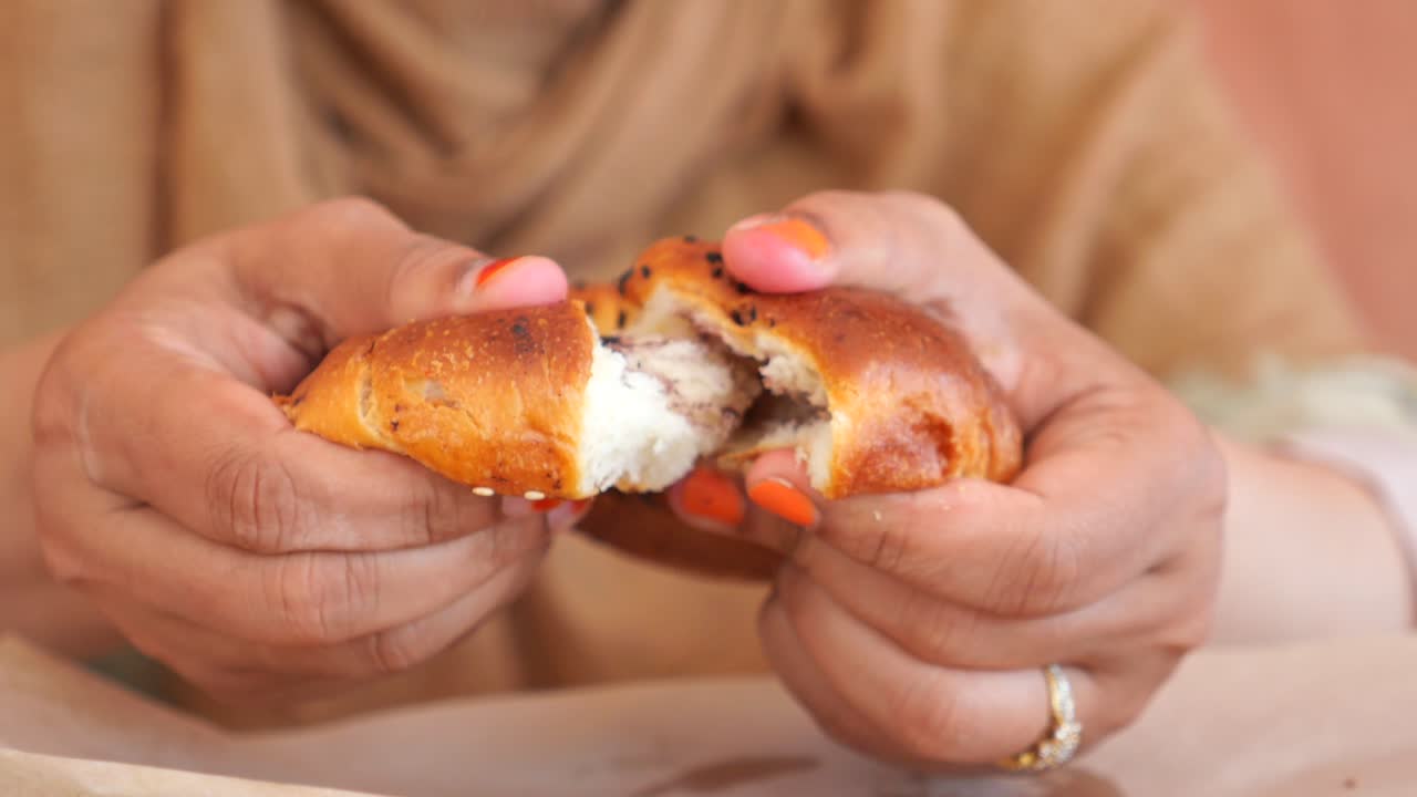 una mujer comiendo un pan dividido.