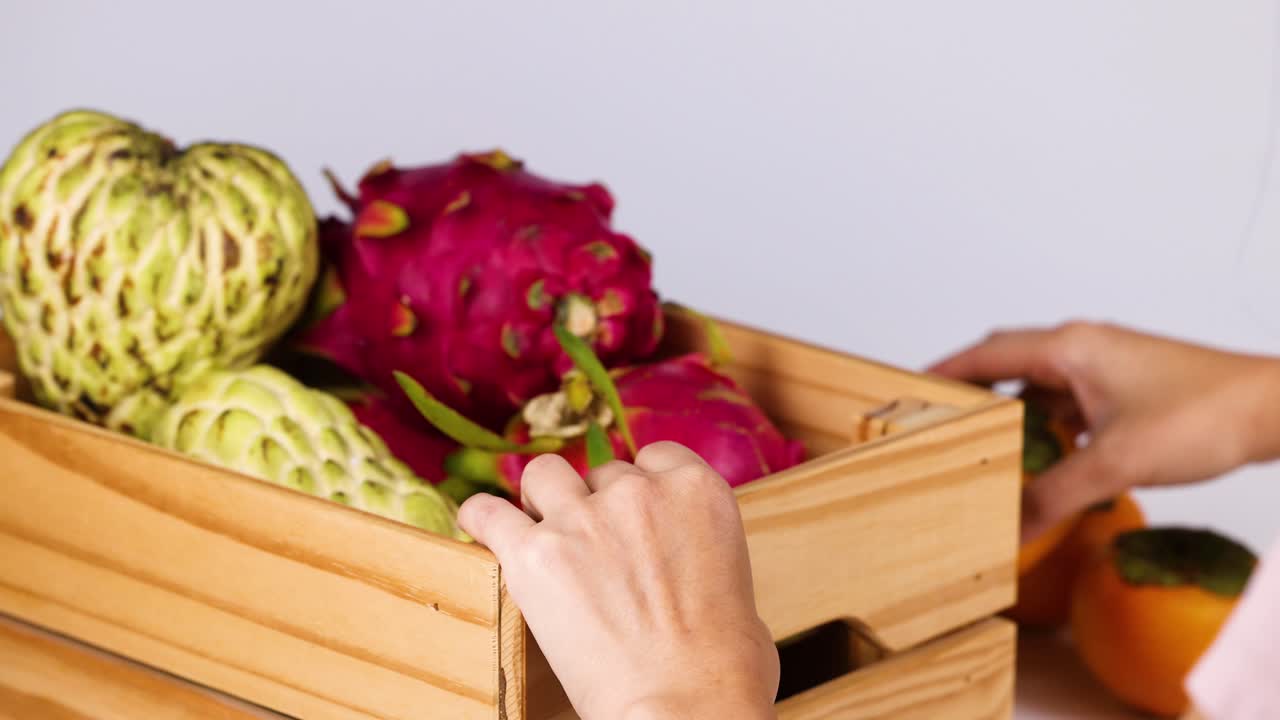 Hand selecting persimmon from wooden crate