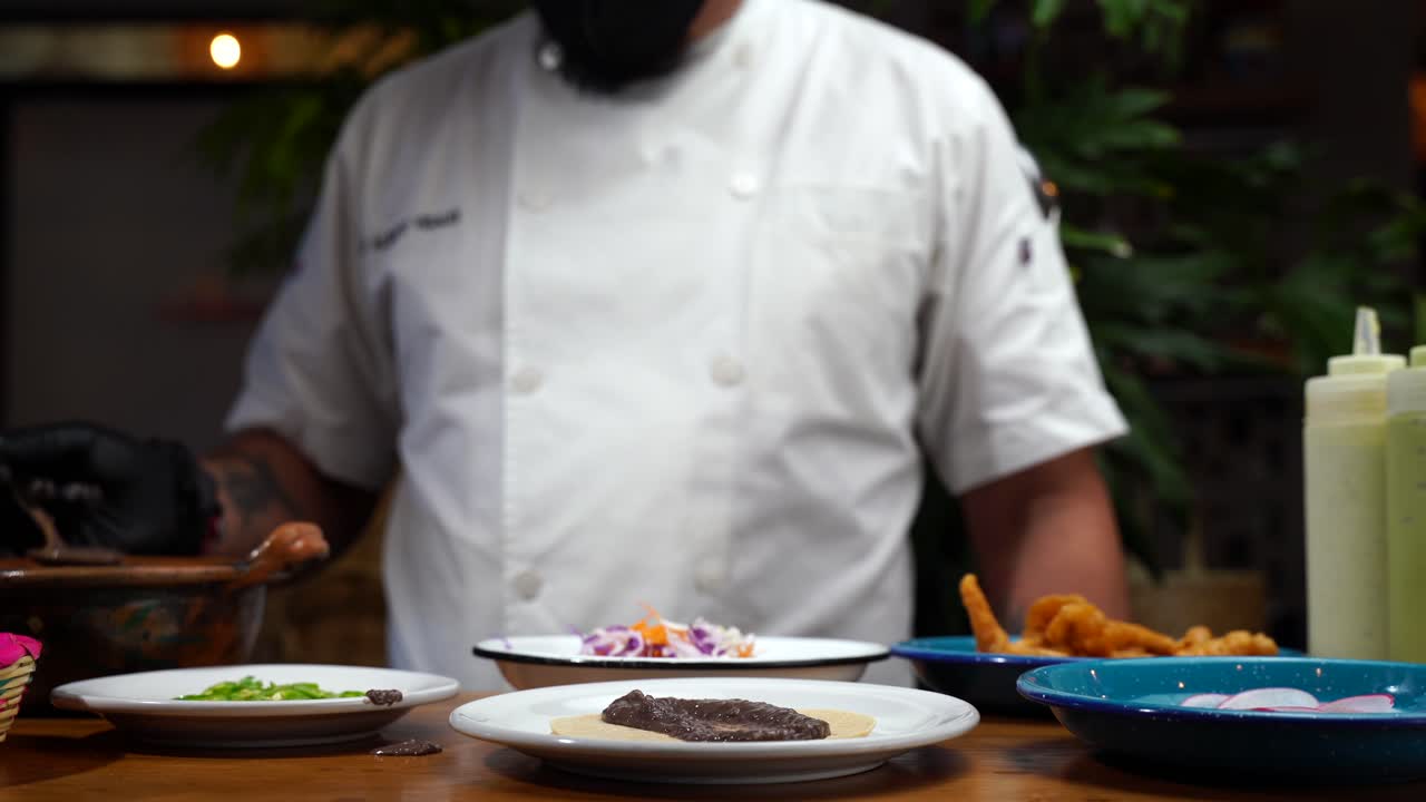 Chef adding beans on top of tortilla in mexican restaurant
