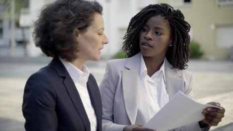 Confident-managers-discussing-documents-on-street