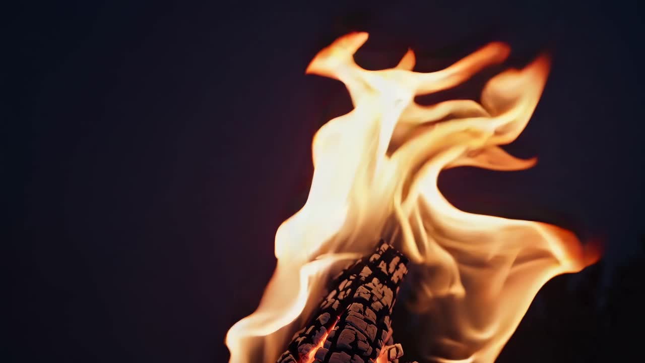 Close-up shot of vibrant flames against a dark background, capturing dynamic movement and warmth