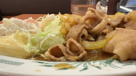 a close-up view of a ginger pork plate showcases its caramelized edges and tender texture, served fresh in a local tokyo eatery with a relaxed, inviting atmosphere.