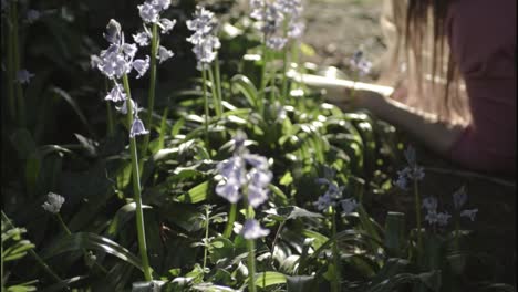 Frau-Liest-Ein-Buch-Im-Garten-Mit-Glockenblumen