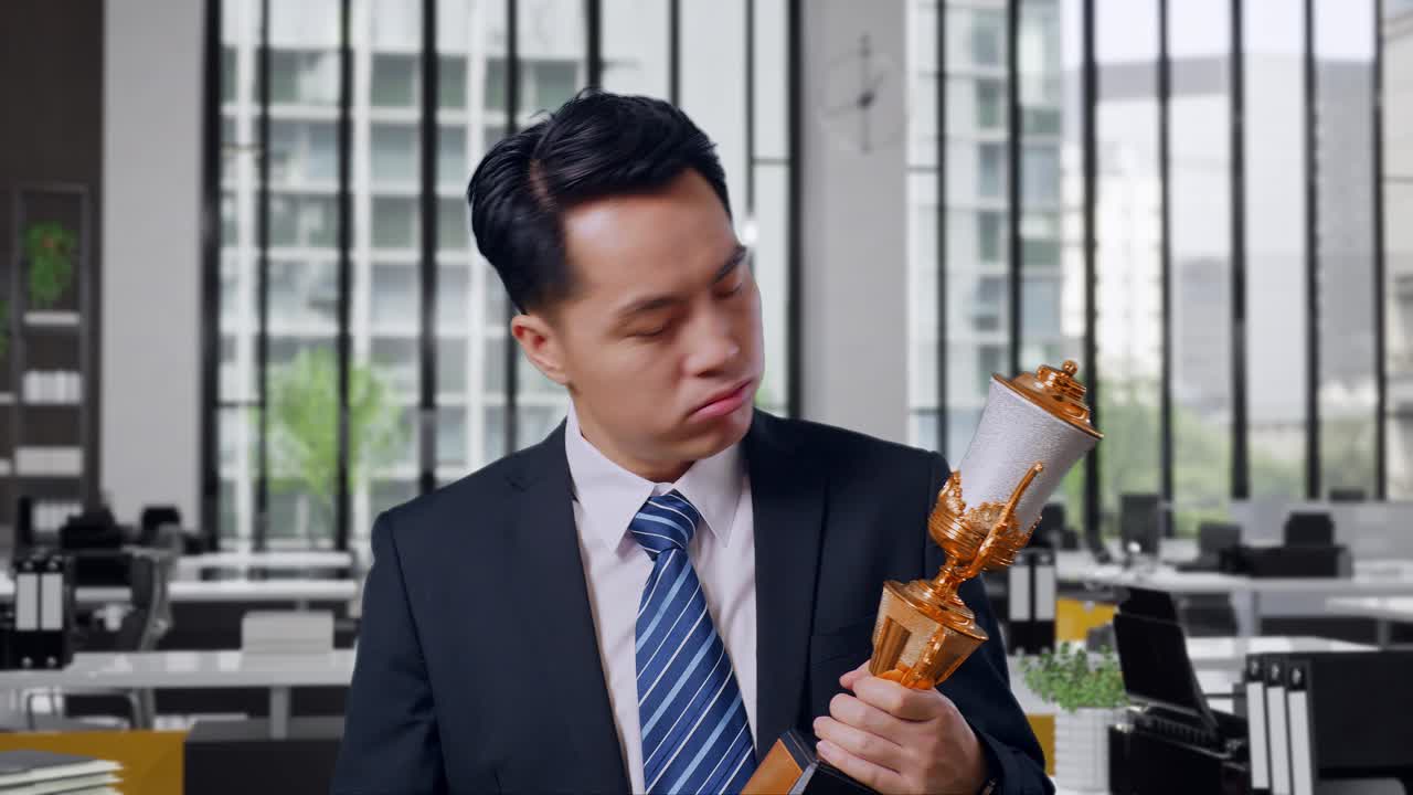 Businessman holding a trophy in the office