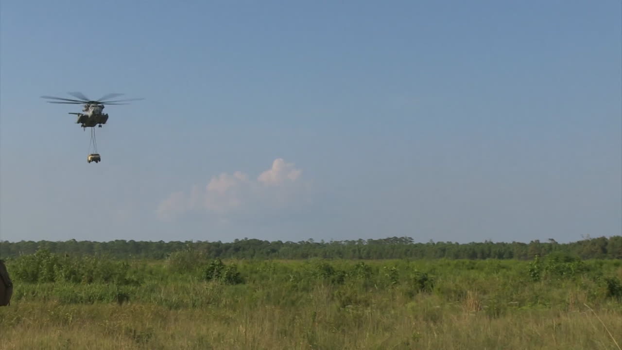 sikorsky ch53 헬리콥터가 들판에서 험비를 들어 올리고 떨어뜨립니다.