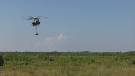 the sikorsky ch53 helicopter lifts and drops a humvee in a field