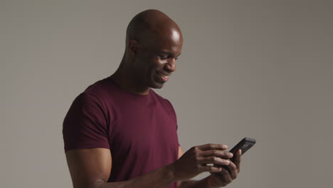 studio shot of smiling mature man with mobile phone getting good news against grey background 1