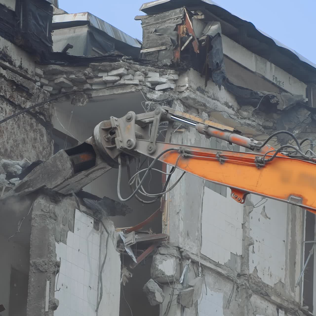 Breaking concrete walls and floors with the help of machinery. Dusty area of destruction site. Powerful claw ruins the house. View from below