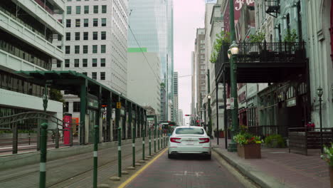 driving car slowly on main street in downtown of houston passing congress street. driving pass preston nb metro station and 990 congress. following white car go through the historic houston areas.
