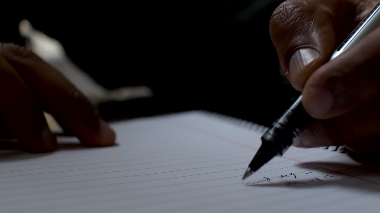 Close-up of a person writing on paper using a pen, creating a list with their left hand, highlighting the unique perspective of left-handed writing