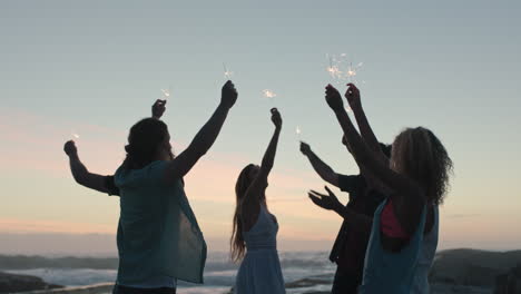 friends holding sparklers on beach celebrating dancing sunset party