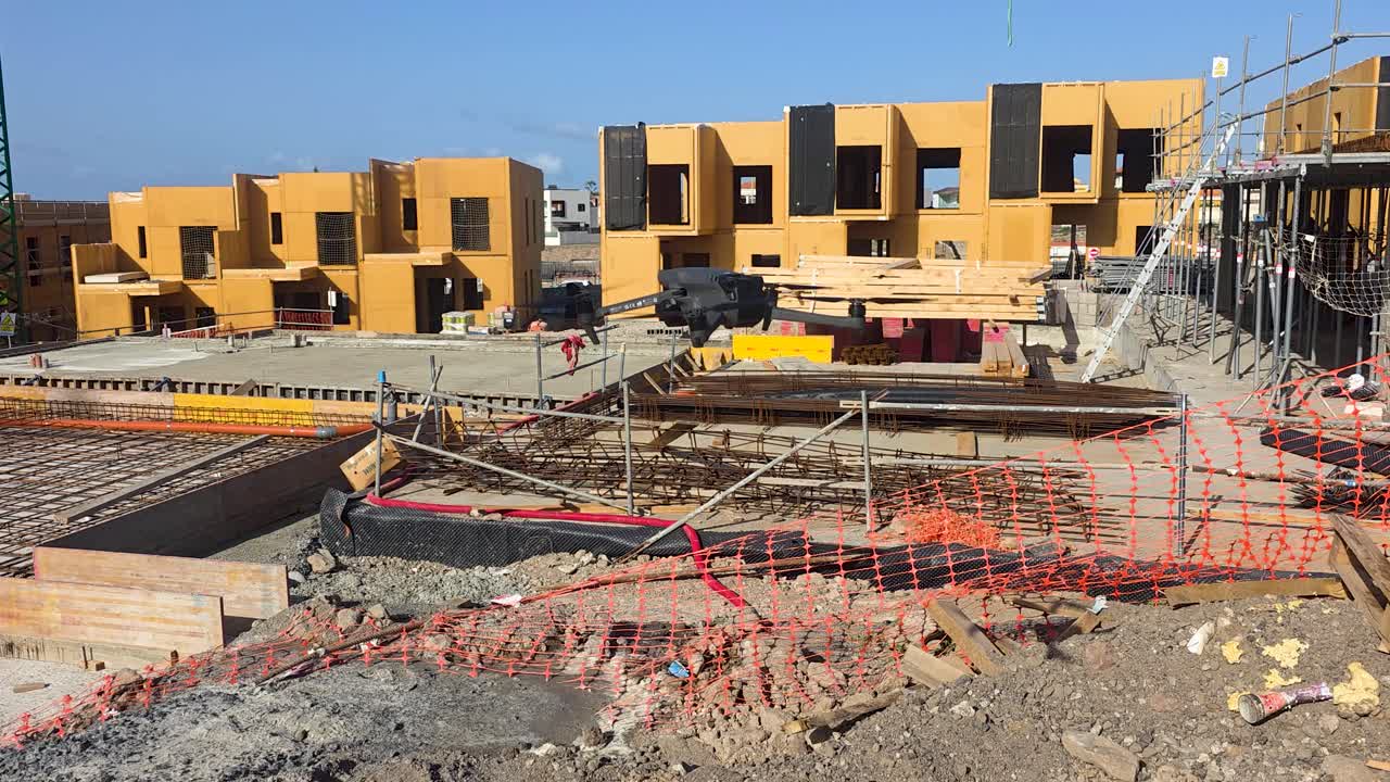 Drone captures ongoing construction at a housing site with vibrant yellow structures. Useful for real estate updates or urban development content