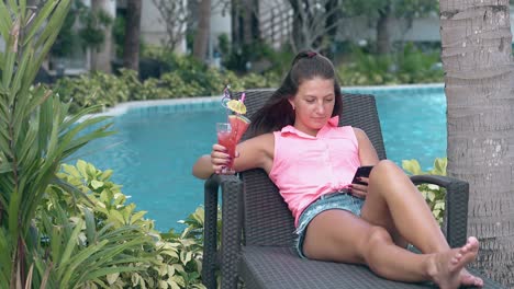 woman relaxes on brown lounge chair near thick palm trunk