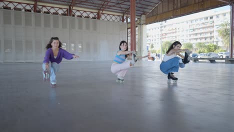 three women roller skating in a covered urban space