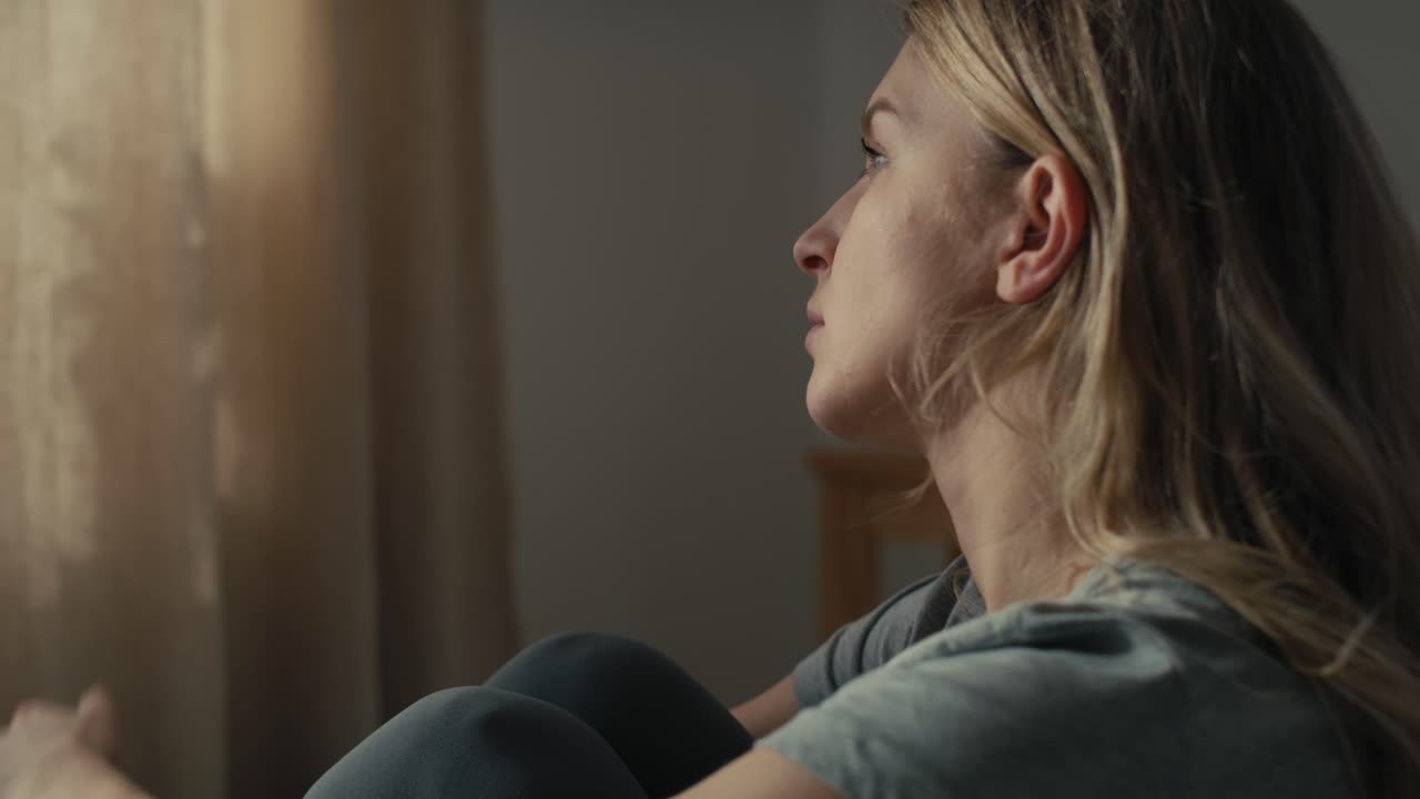 mujer caucásica con salud mental sentada en la cama y mirando hacia otro lado