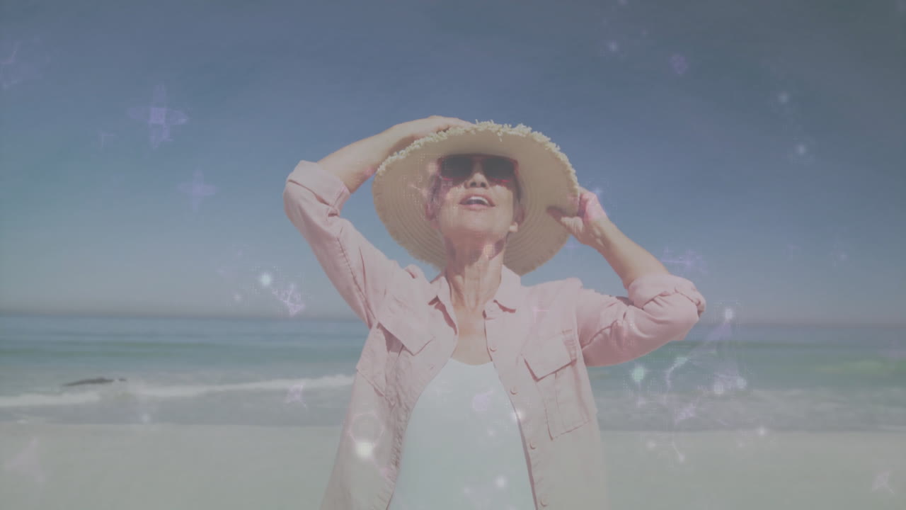 Senior woman standing on beach holding hat, with animated health graphs and sun icons floating