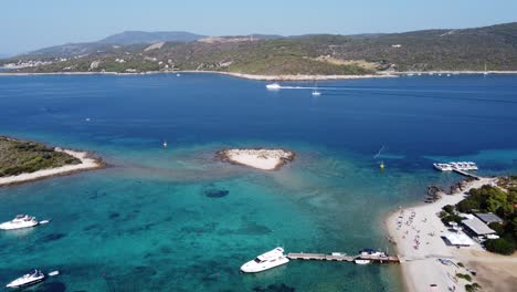 personas relajándose en la playa de la laguna azul de la isla de veliki budikovac con sus yates anclados en la bahía del archipiélago