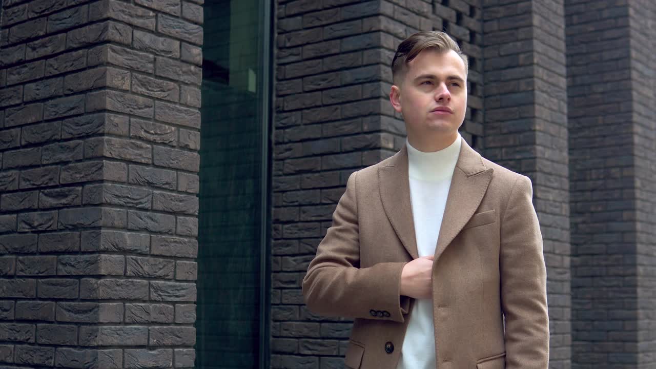 Stylish young man in brown coat with pocket watch on the street