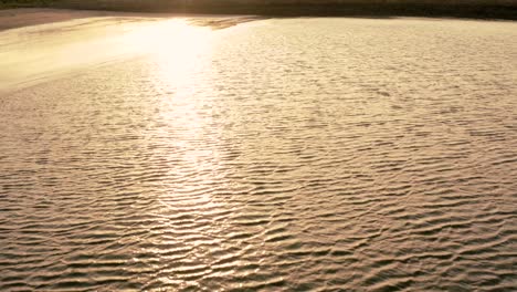 a tropical sandy beach, with rippling waves at sunset