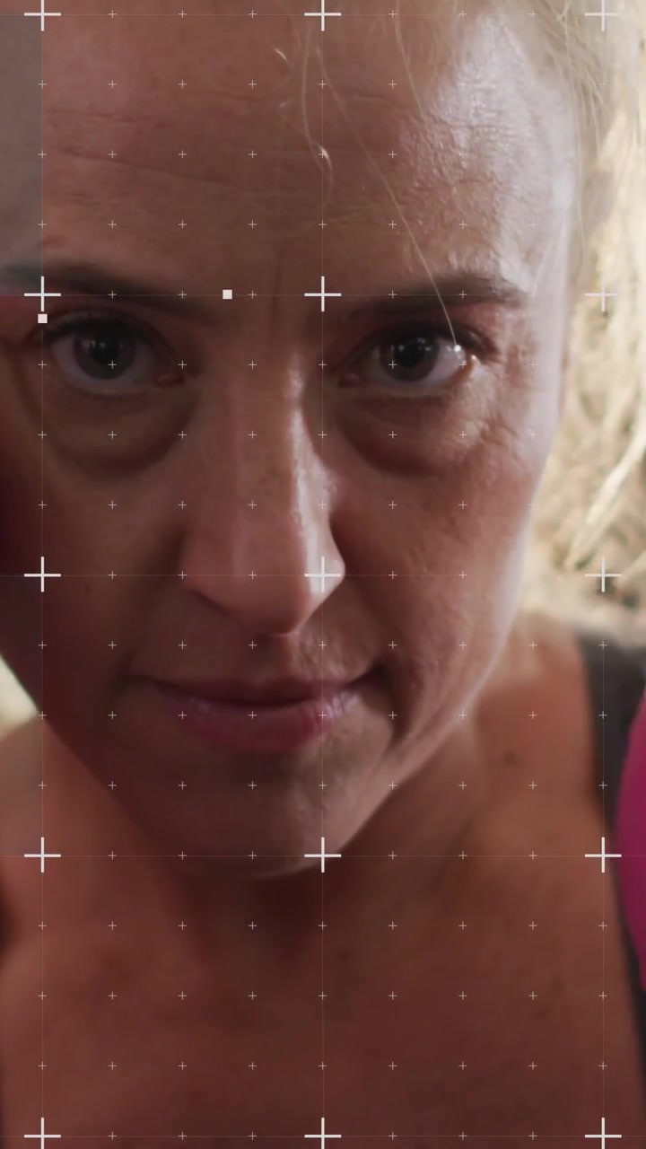 Video verticale: Donna che sferra jab di boxe con un guantone rosa, attraversando l'obiettivo, con punti AR che tracciano il guantone per il fitness.