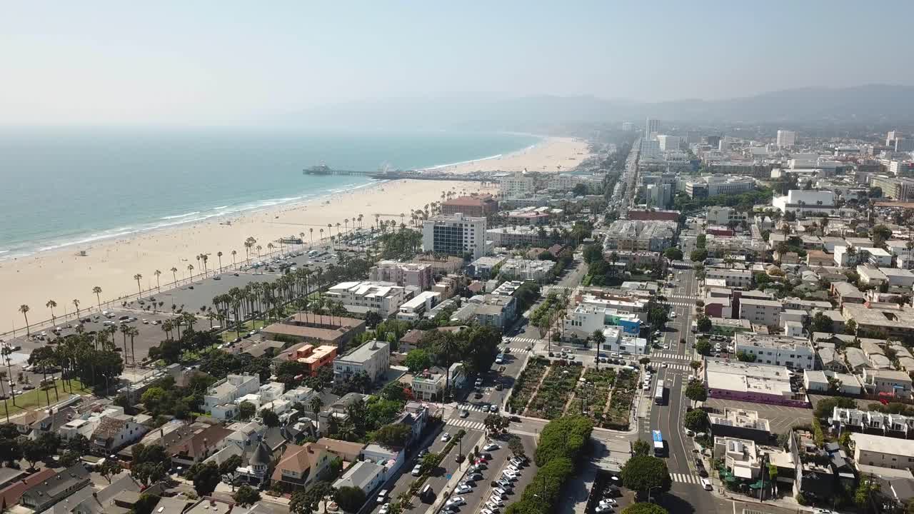Drone in volo all'indietro che rivela la costa delle spiagge di Venice e Santa Monica
