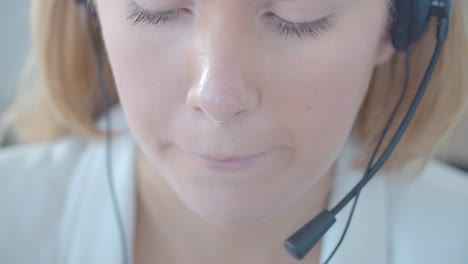 cara de una joven operadora de centro de llamadas rubia en auriculares