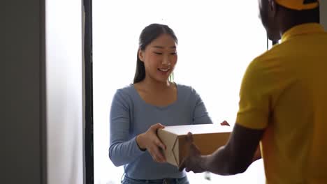 A customer receives a package at their home entrance from a delivery person. The interaction takes place on a bright, sunny day, showcasing convenience and service.