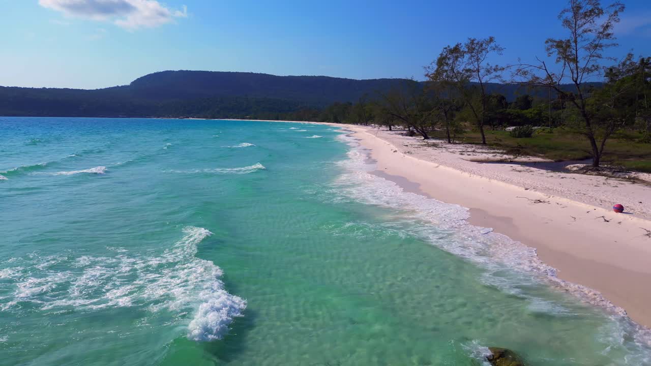 Tropical landscape showing turquoise sea washing white sand beach and green rainforest covering Koh Rong island in Cambodia. Spectacular aerial view flight ascending drone