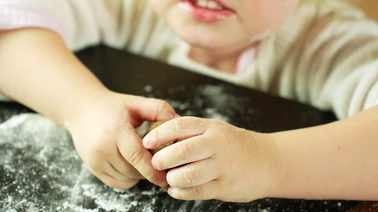 Child kneading gingerbread dough in a kitchen on a black table with flour, preparing festive cookies for christmas, Concept of holiday baking, family traditions