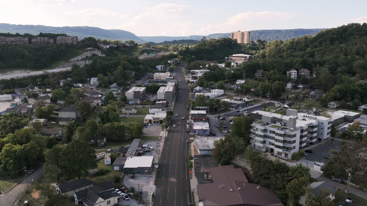 An aerial view of Cherokee Boulevard in Chattanooga, Tennessee, showing light traffic winding through the city framed by lush green hills and modern buildings