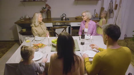 little girl bringing pie to the table during a dinner with her happy family