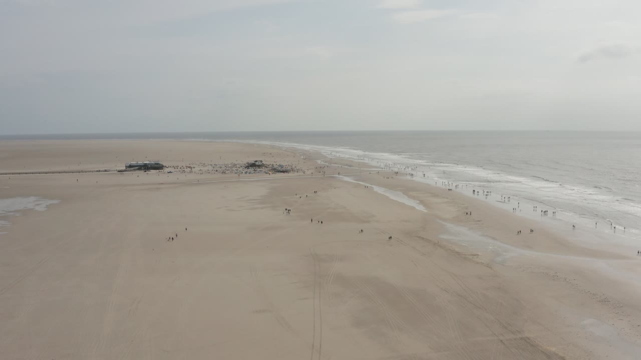 Cinematic drone - aerial panorama circling shot of the sandy beach with tourists and people in St. Peter Ording at the north sea, schleswig holstein, germany, 30p