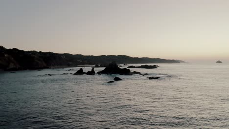 Aerial-view-of-breathtaking-coastline-of-Mazute-in-Mexico-with-crashing-waves-during-dusk-and-sunset-light