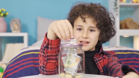 el chico ahorra dinero en la alcancía para sus sueños.