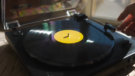 guy putting a vinyl on a record player at home - wide angle