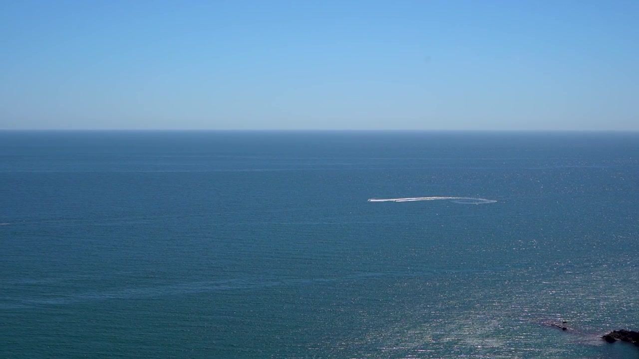Amplia vista al océano con un barco y cielo despejado, que evoca serenidad y exploración.