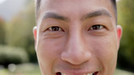 portrait close up of happy biracial man smiling in sunny garden, in slow motion