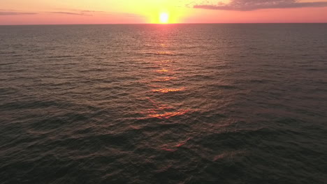 cinematic drone shot of the ocean with the sun setting or rising on the atlantic ocean, tilting up