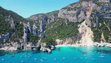 los barcos turísticos disfrutan de las vacaciones de verano en las formaciones rocosas de la playa de cala goloritze en cerdeña, italia - antena 4k