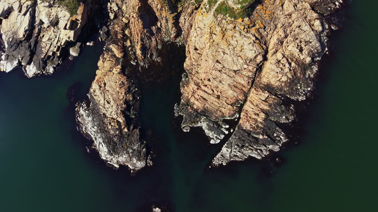 Costa rocciosa con acqua limpida e il sole che splende sulle rocce di giorno vicino alla riva.