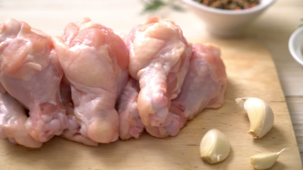 Alas de pollo crudo fresco sobre tabla de madera con ingredientes