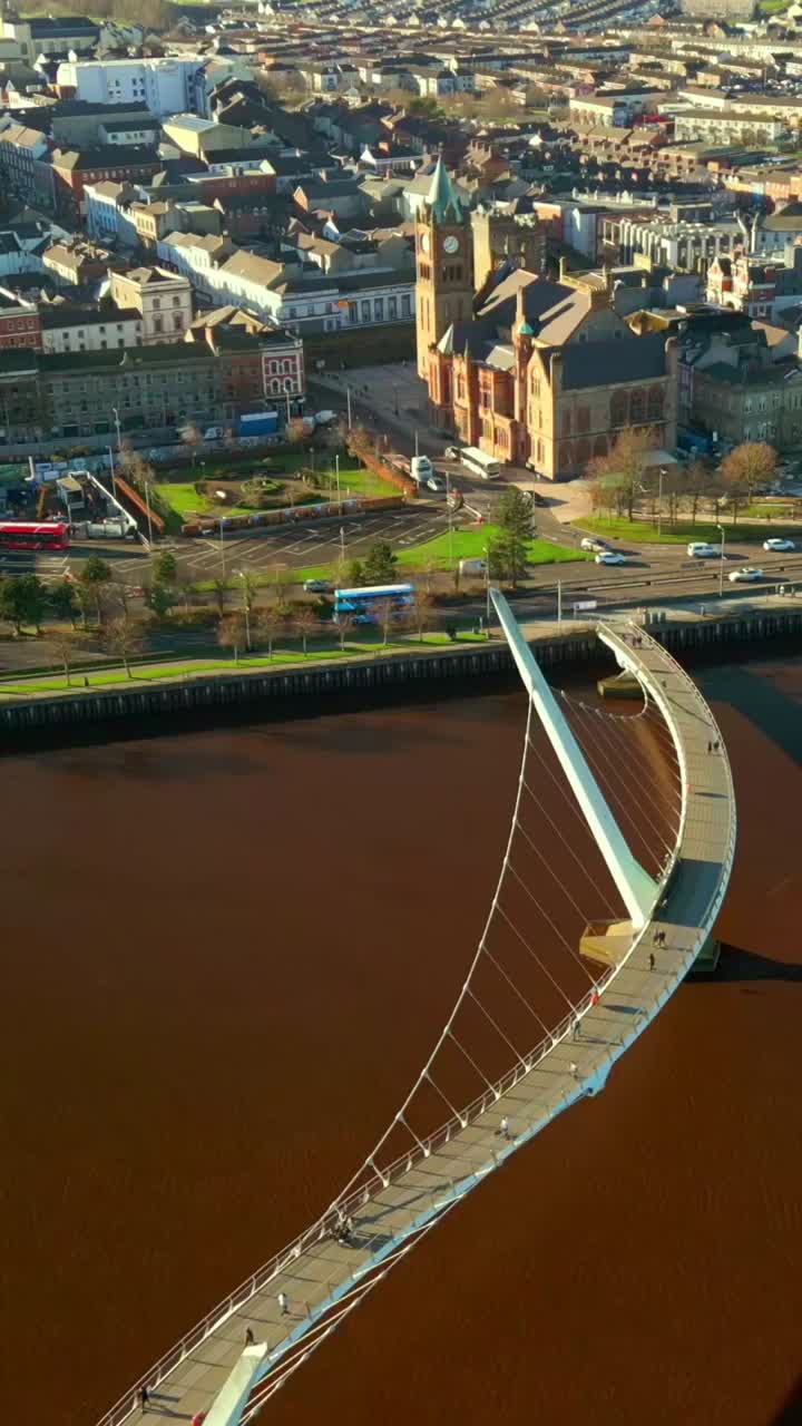 Wide overhead social ratio aerial of the Peace Bridge over the River Foyle in Derry, AKA Londonderry in Northern Ireland. Filmed in 1080x1920, 60FPS and with Rec709 color