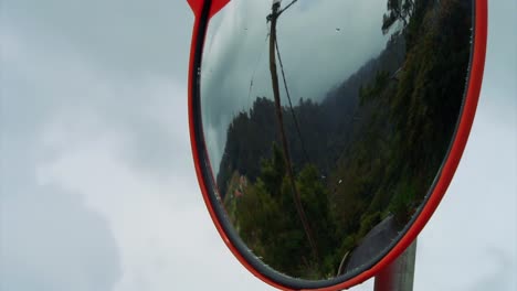 footage of a mirror reflecting a car passing through the country side