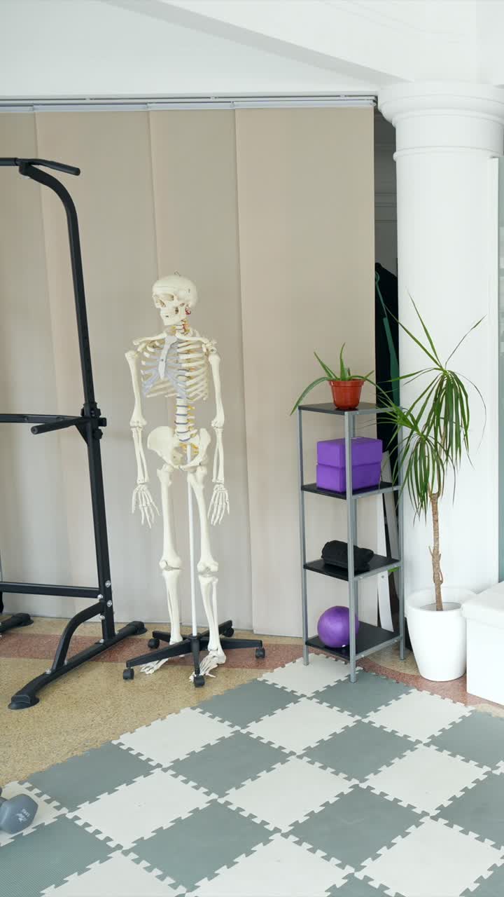 Plano Panorâmico de uma Academia Residencial com Equipamentos de Ginástica e Modelo de Esqueleto
