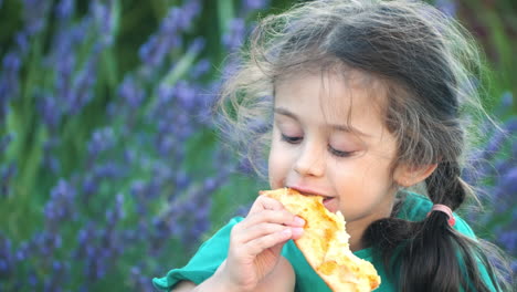 niña pequeña comiendo pizza al aire libre